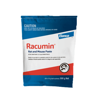 Racumin Rat and Mouse Paste rodenticide sachets in 500g packaging on a farm shed floor.